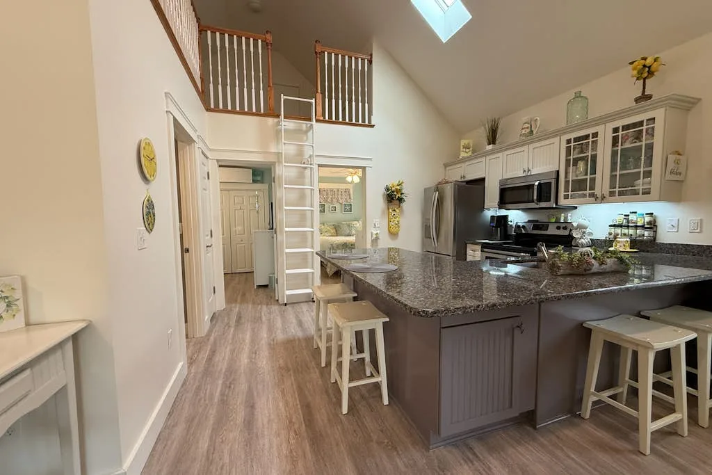 A bright kitchen with a large island, bar seating, and a high ceiling.
