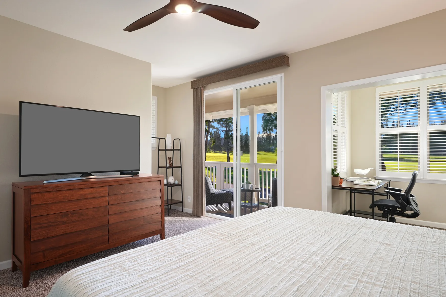 Un dormitorio con una cama grande, televisor y puertas corredizas de vidrio que dan a un balcón.