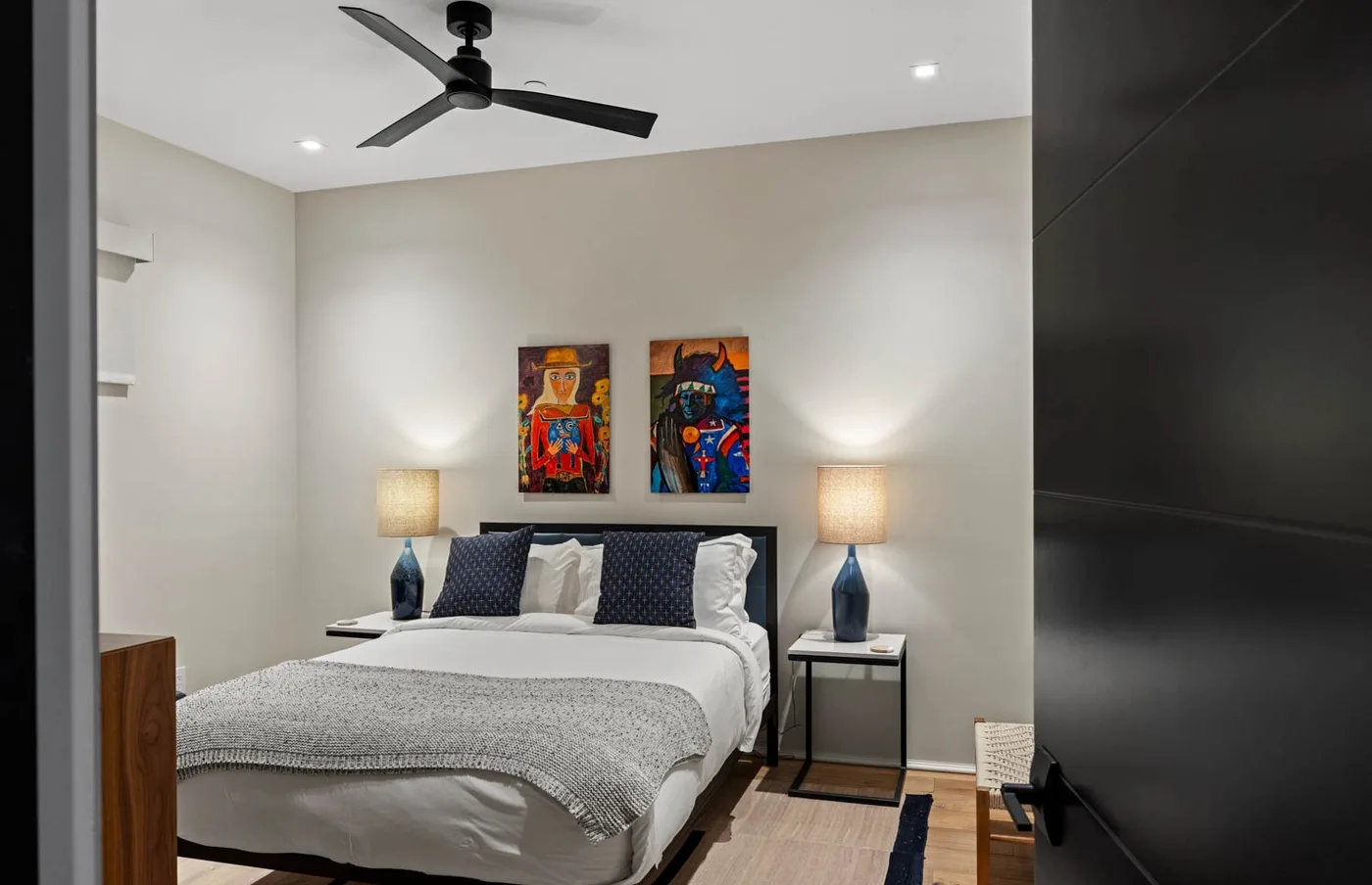 A bedroom with a neatly made bed and colorful artwork above the headboard.