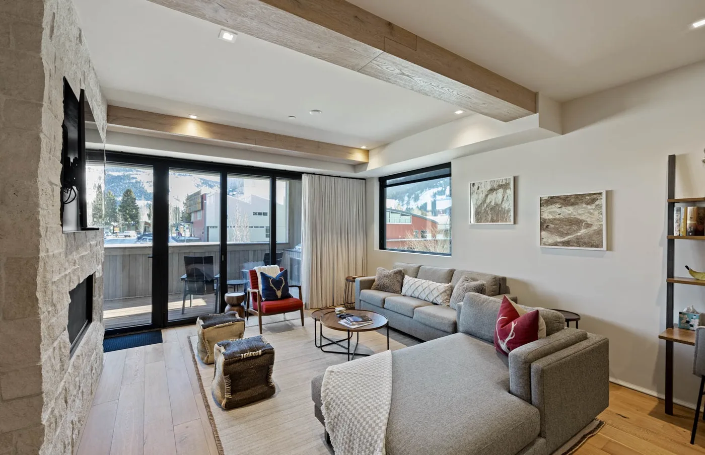 A bright living room with a sectional sofa, armchair, and large windows.