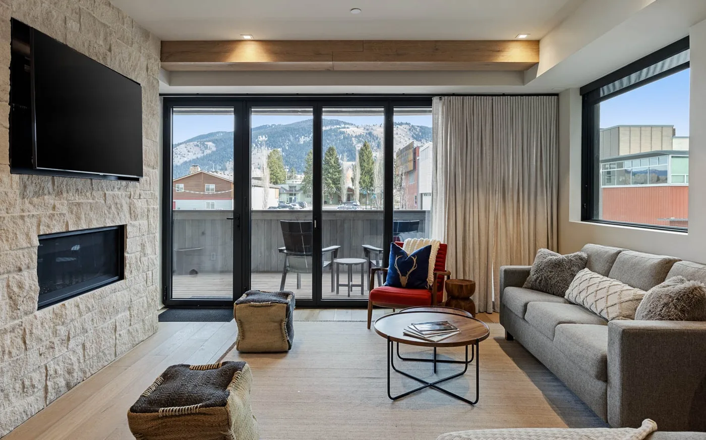A living room with seating, a television, and large windows overlooking the mountains.