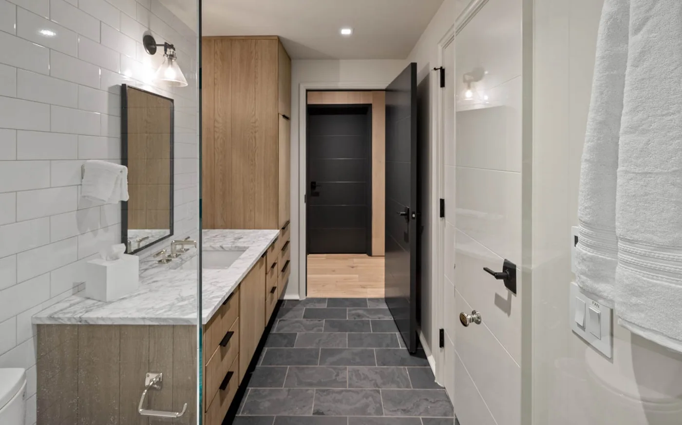 A tiled bathroom with a long vanity, mirror, and shower.