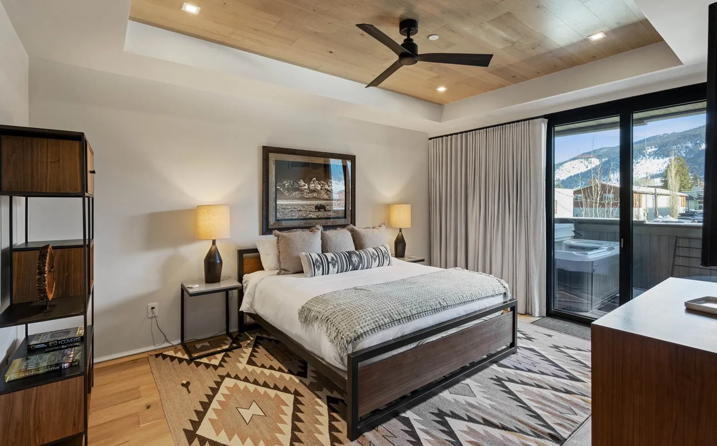 A bedroom with a bed, bedside lamps, and sliding glass doors opening to a balcony.