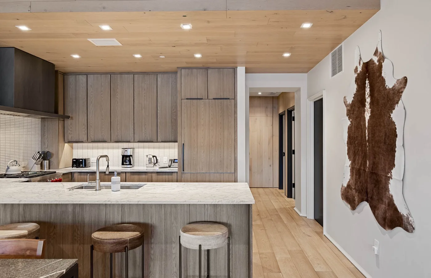 A modern kitchen with a wide island and a hallway beside it.
