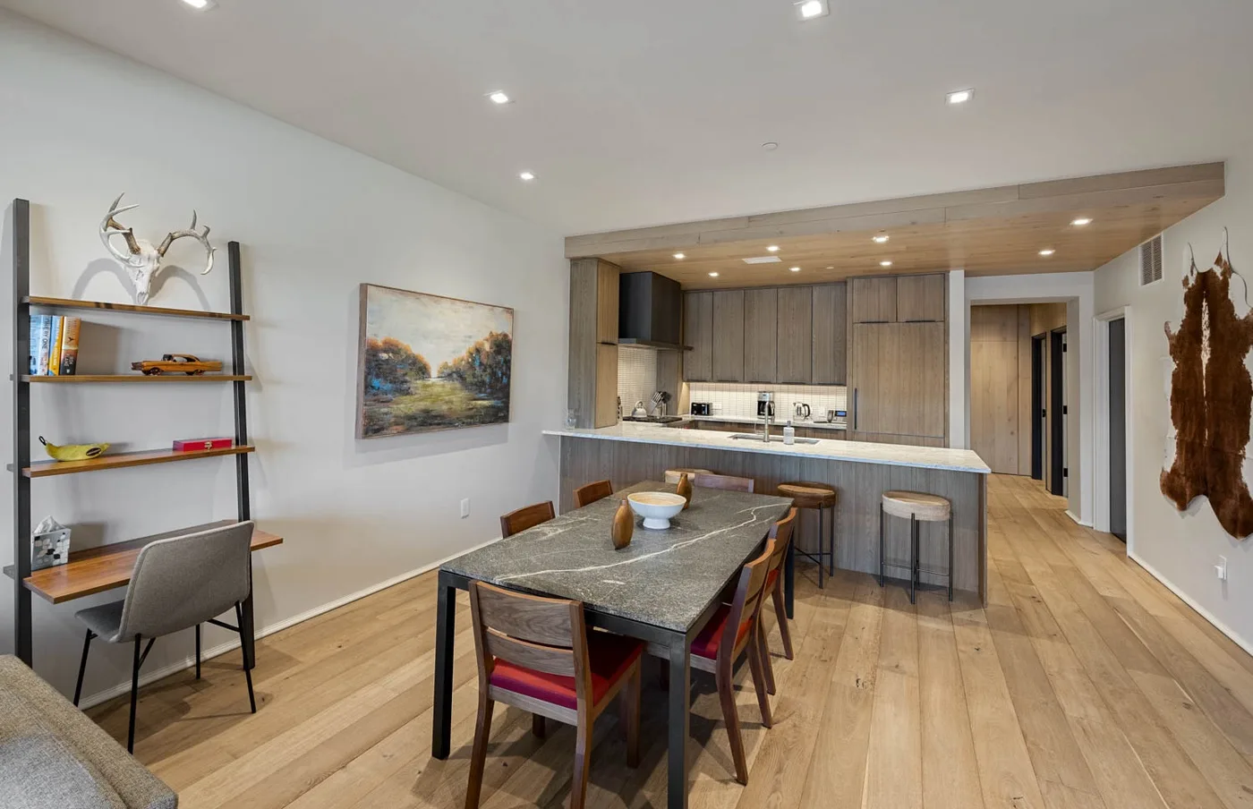 An open-plan kitchen and dining area with a long table and wooden flooring.