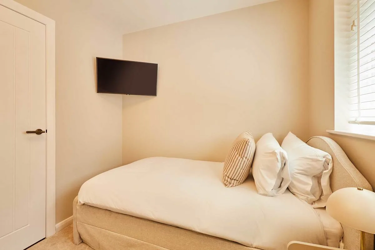 A bedroom with a bed, pillows, and a wall-mounted television.