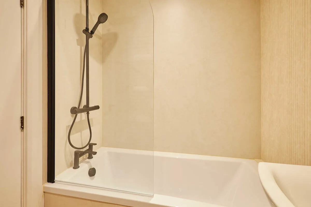 A bathroom shower with a handheld showerhead beside the bathtub.