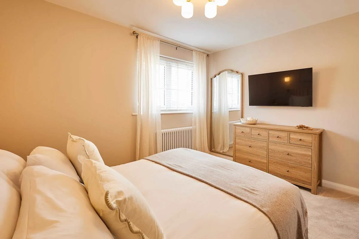 A bedroom with a bed, window, and wall-mounted television.