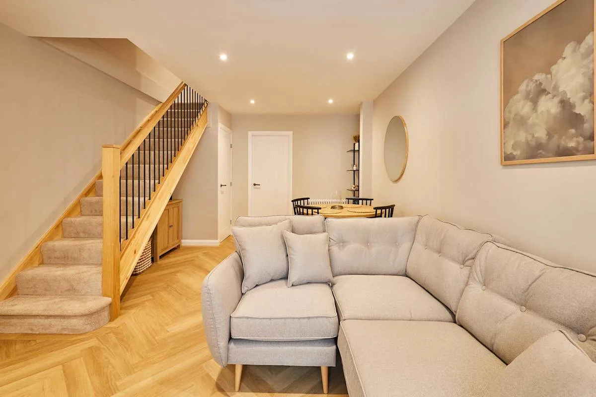 A living room with a sectional seating area and a staircase.