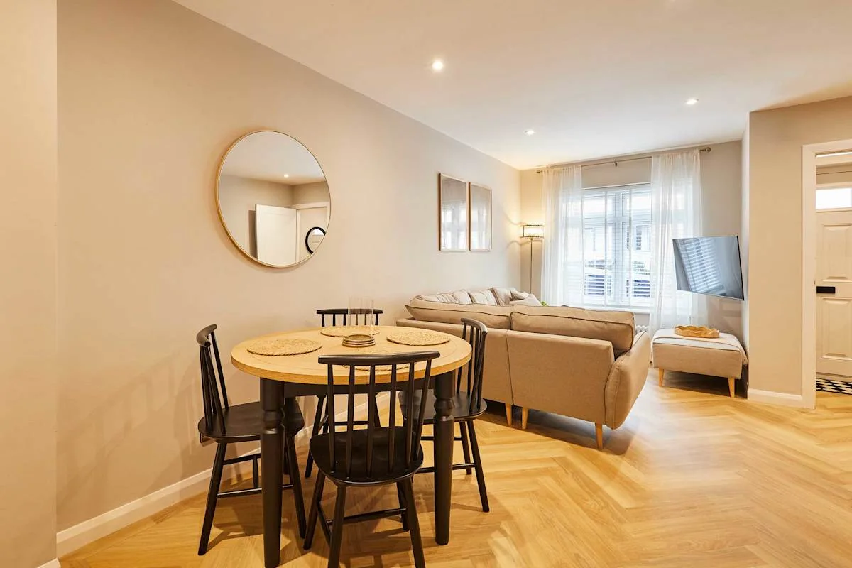 A bright living and dining area with a round table and seating.