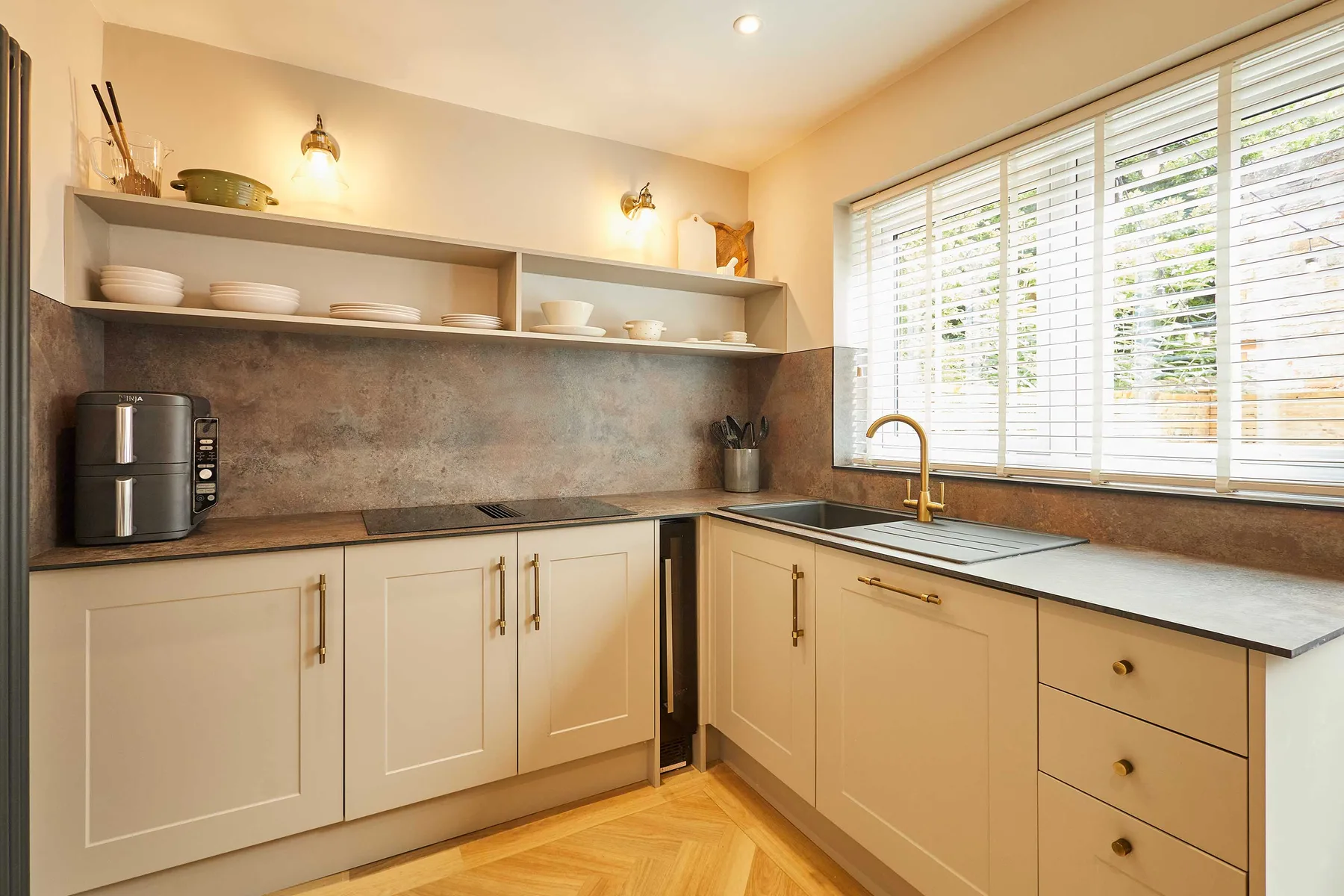 A bright kitchen with pale cabinets, open shelving, and a large window.