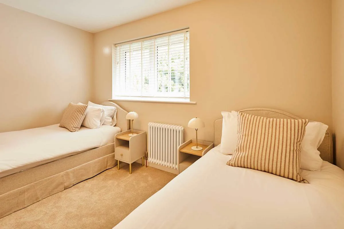 A bedroom with two beds, a window, and a radiator.