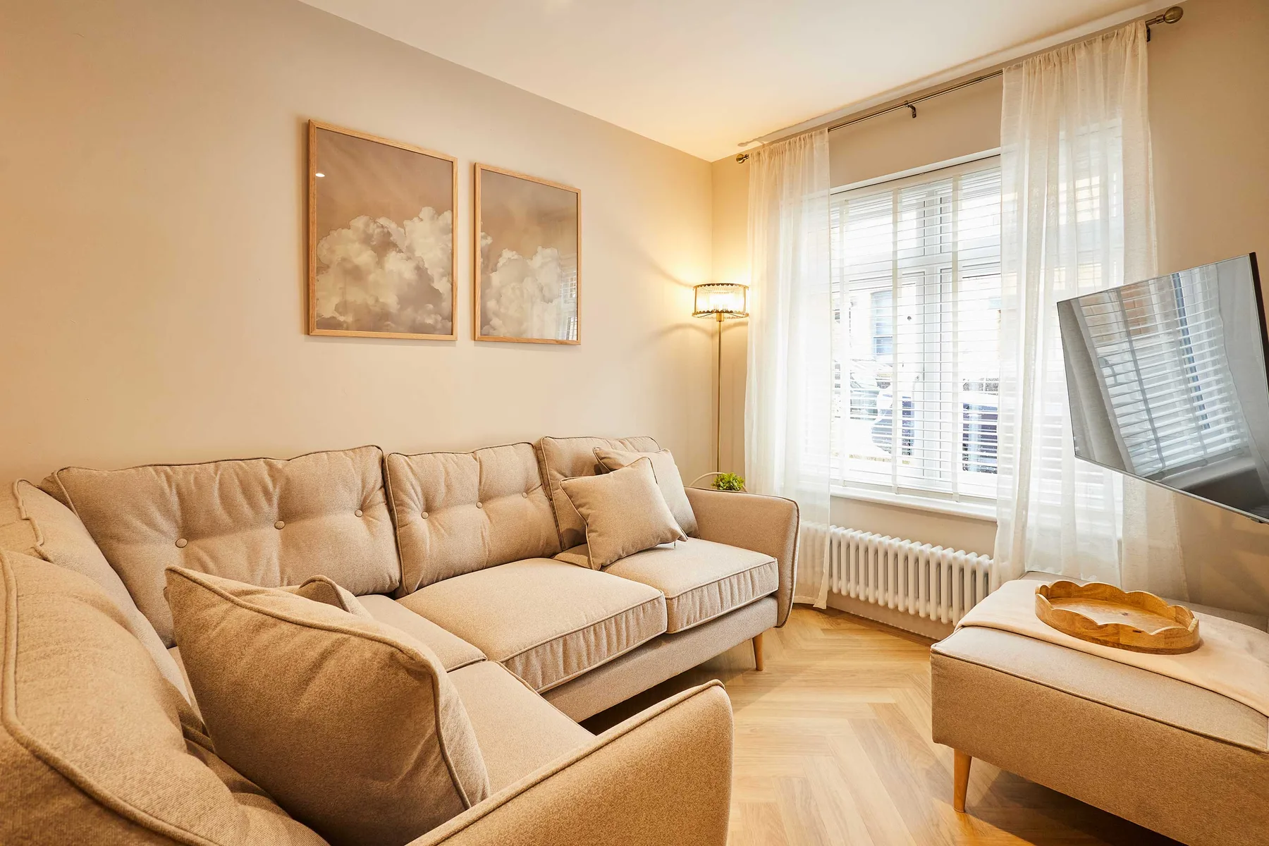 A bright living room with beige seating beside a large window.