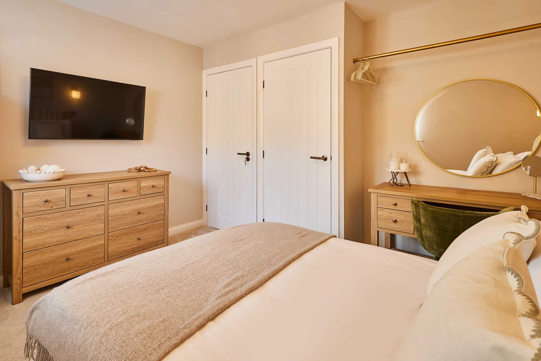A bedroom with a bed, a wall-mounted television, and a wooden dresser.