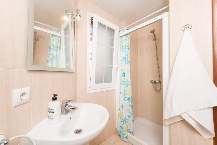 Bathroom with a sink, mirror, and shower behind a patterned curtain.
