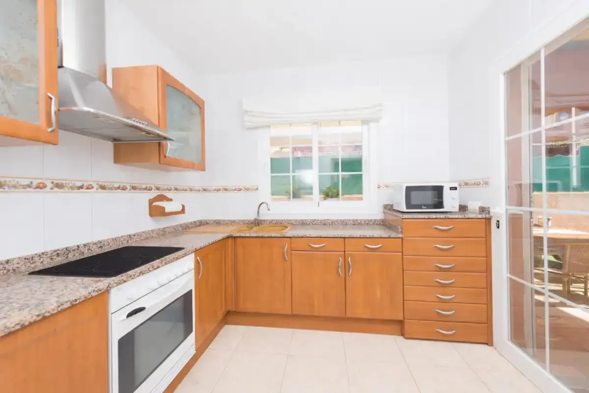 A bright kitchen with wooden cabinets, a countertop, and a microwave.