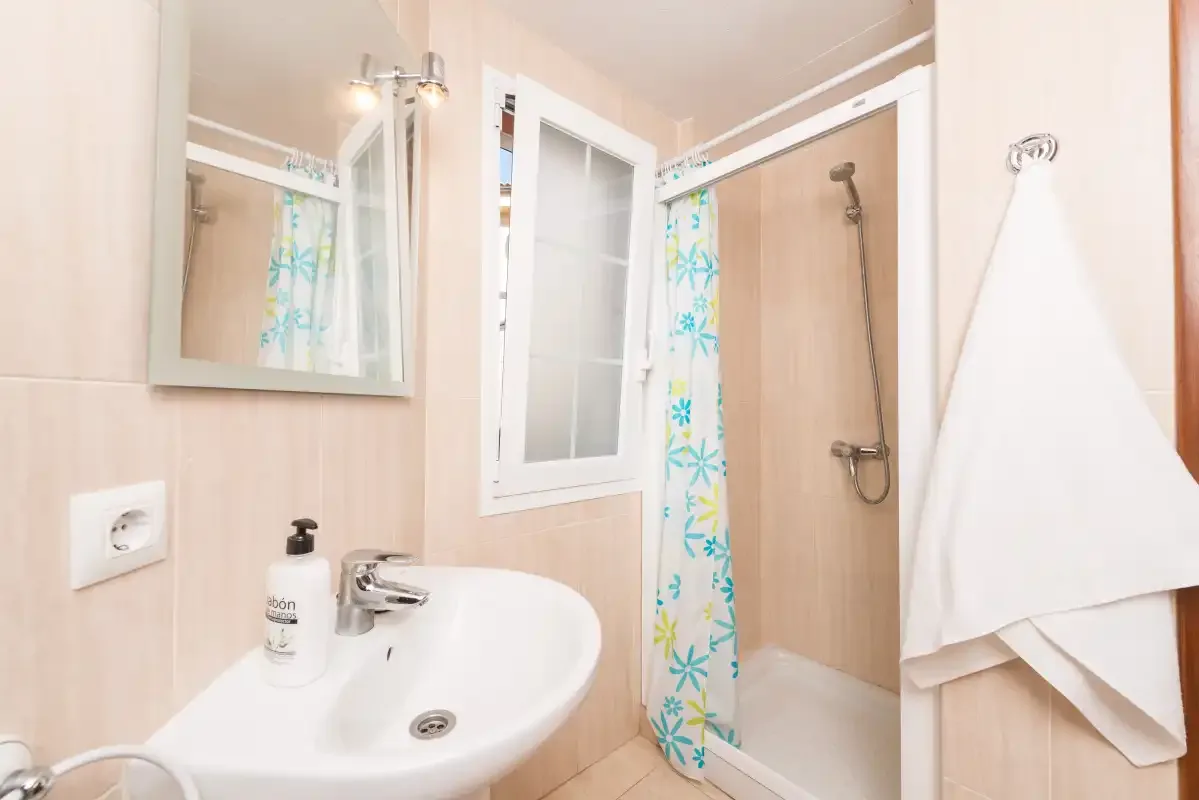 Bathroom with a sink, mirror, and shower behind a patterned curtain.