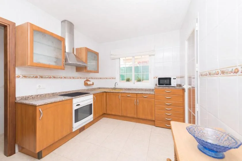A bright kitchen with wooden cabinets, a countertop, and a window.