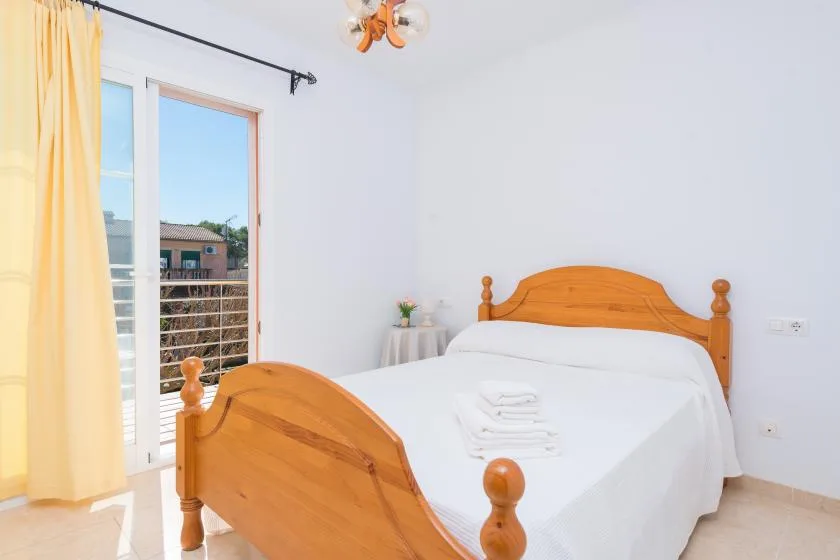 A bright bedroom with a wooden bed and a large window.