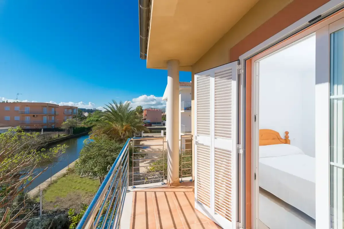 A balcony with metal railings overlooks a canal and nearby buildings.