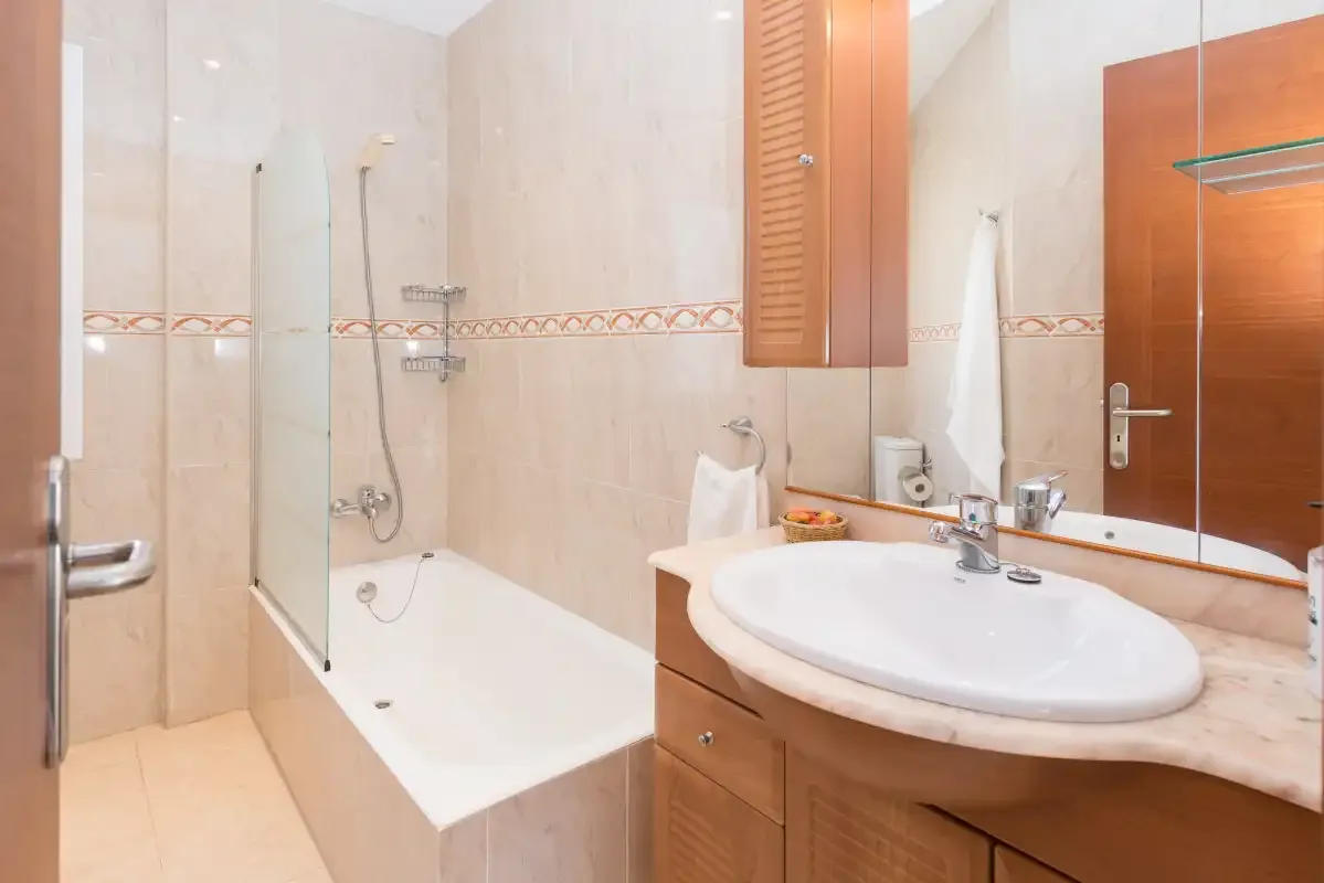 A tiled bathroom with a bathtub, shower fixtures, and a sink.