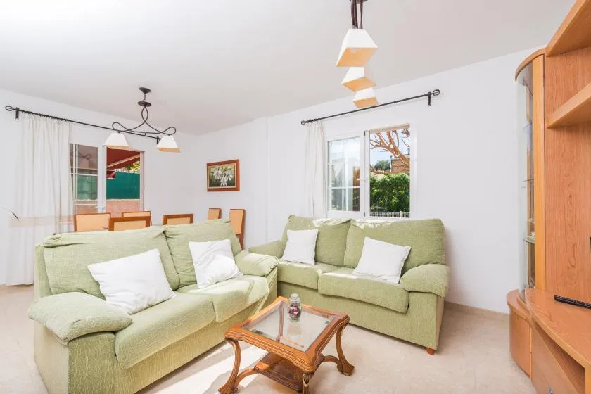 A living room with pale green seating and a glass-topped coffee table.