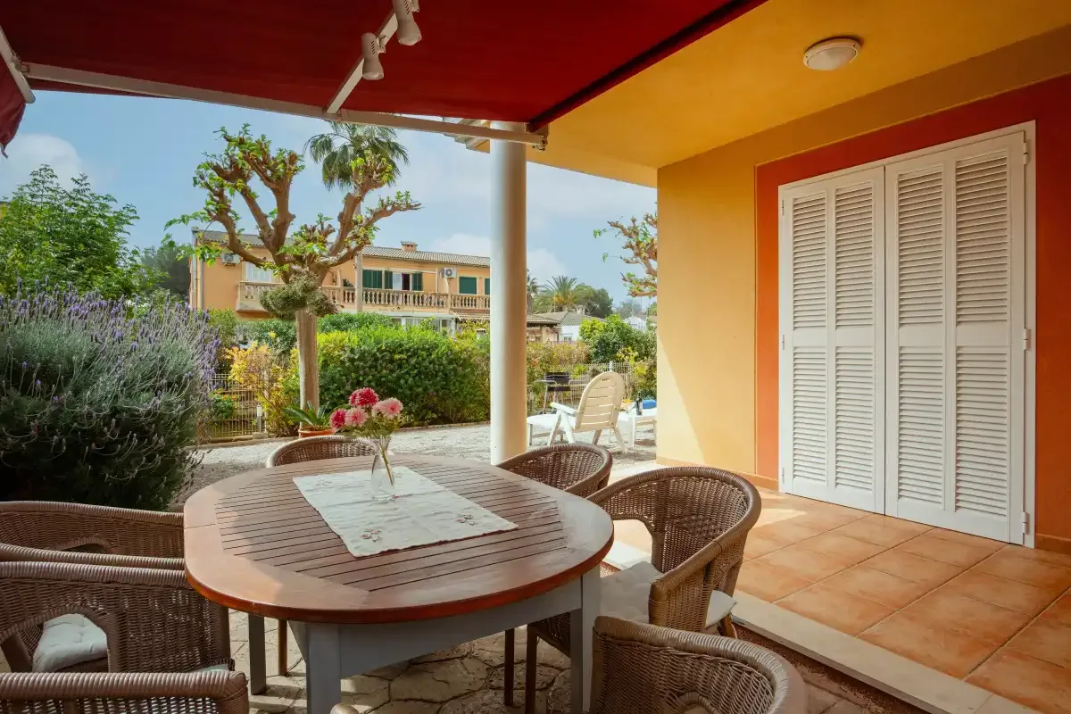A shaded outdoor patio with a table, seating, and garden views.