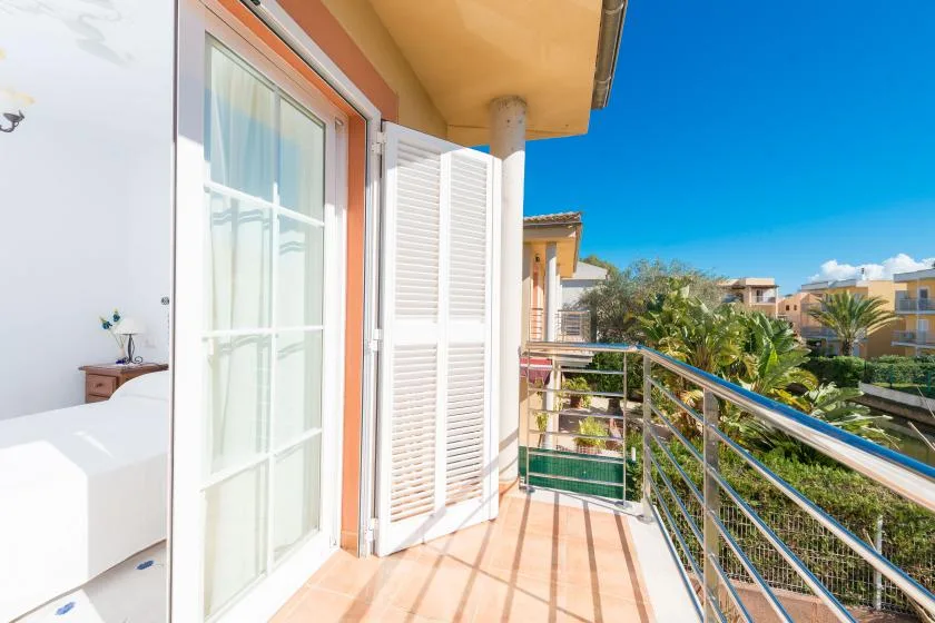 A sunny balcony with a glass door, railing, and views of neighboring buildings.