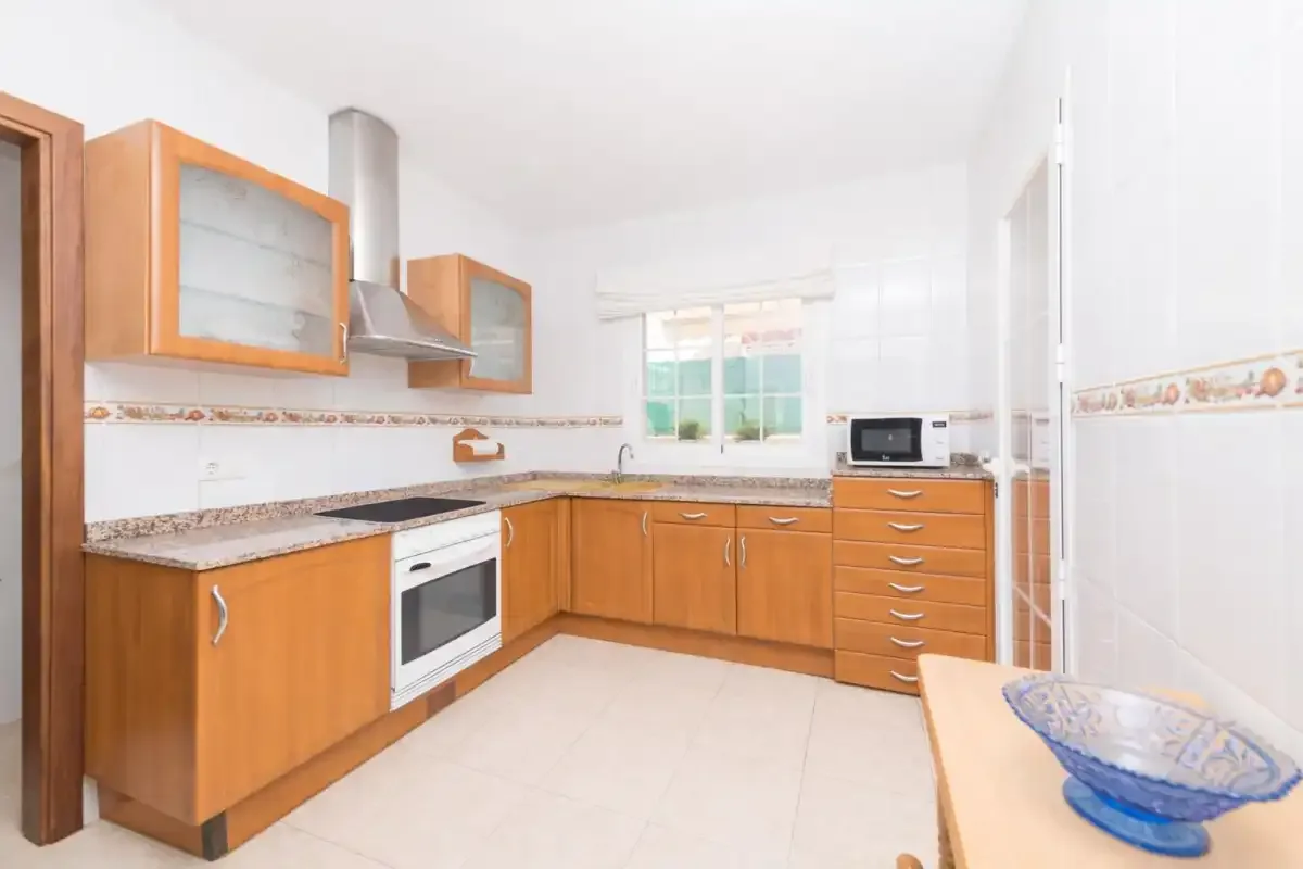 A bright kitchen with wooden cabinets, a countertop, and a window.