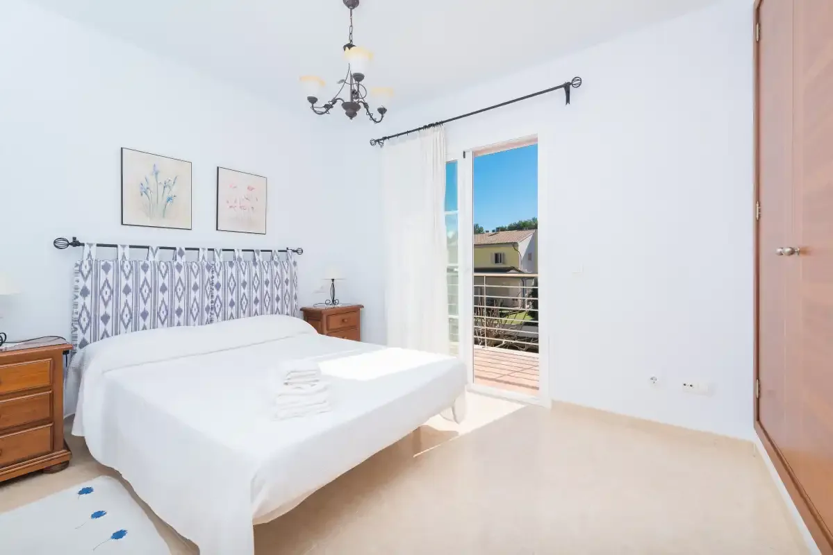 A bright bedroom with a double bed and a glass door opening onto a balcony.
