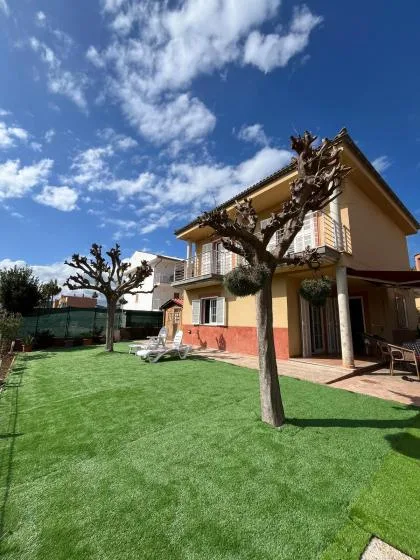 A two-story house overlooks a green lawn beneath a partly cloudy sky.
