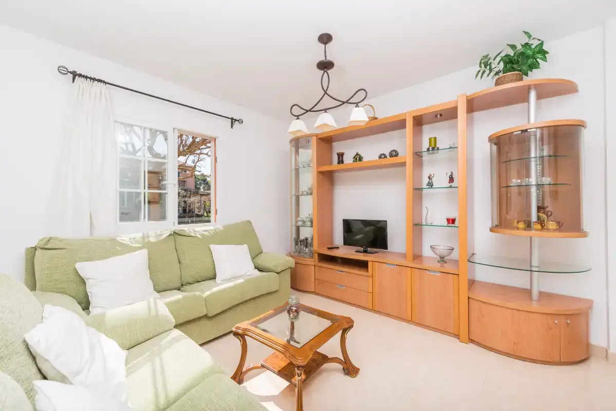 A living room with green seating and a wooden entertainment unit.