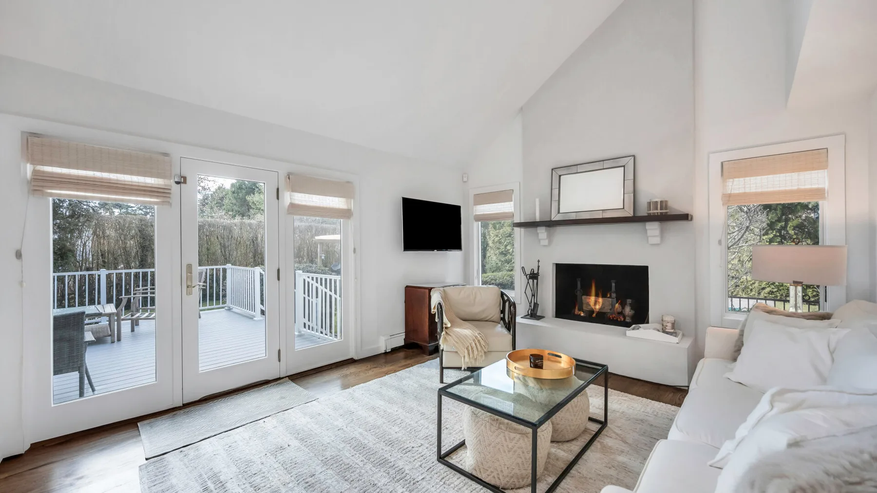 A bright living room with a fireplace, seating, and glass doors opening to a deck.