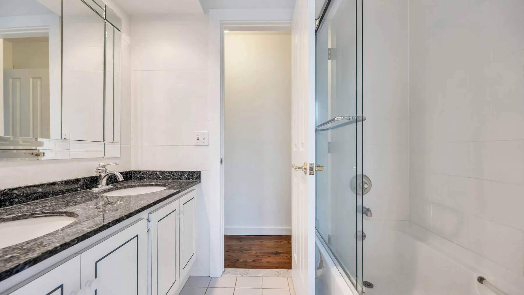 A bright bathroom with a long vanity and a glass shower.