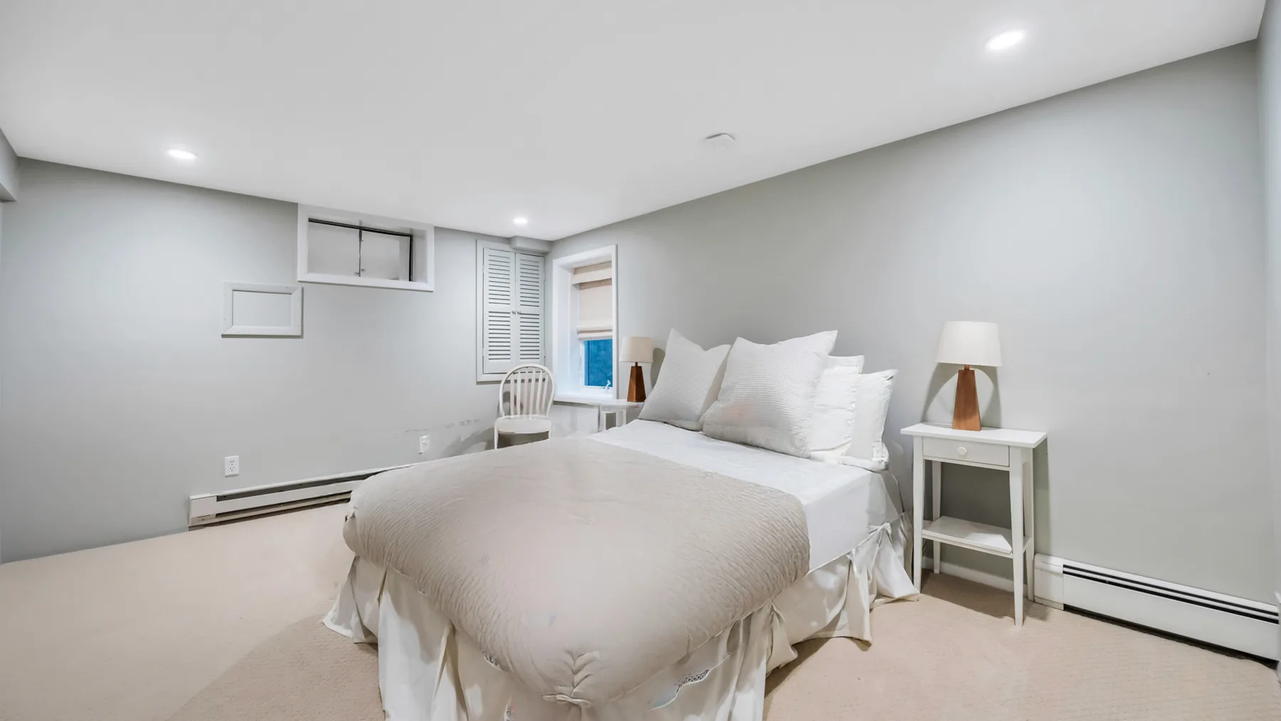 A bright bedroom with a neatly made bed and white bedding.