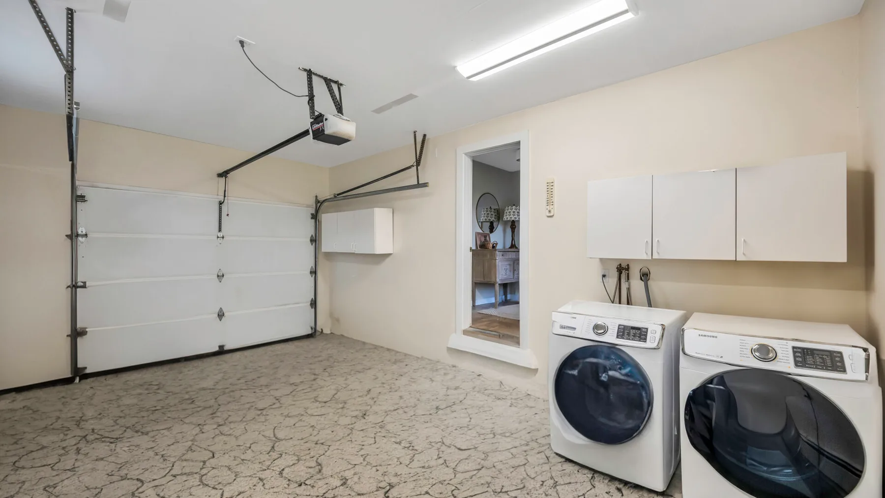 A garage with a closed overhead door and front-loading washer and dryer.