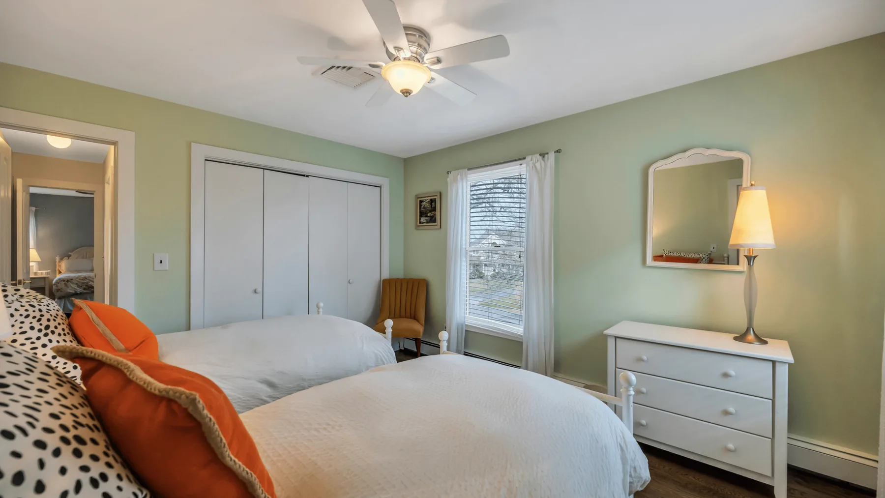 A bedroom with a bed, closet, and dresser beside a window.