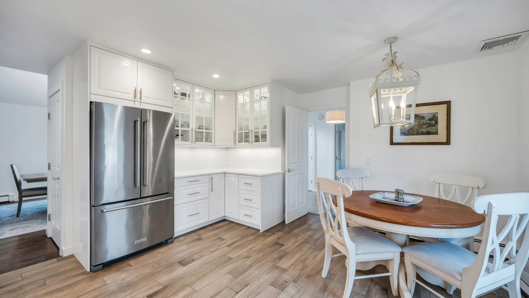 A bright kitchen and dining area with white cabinetry and a wooden table.