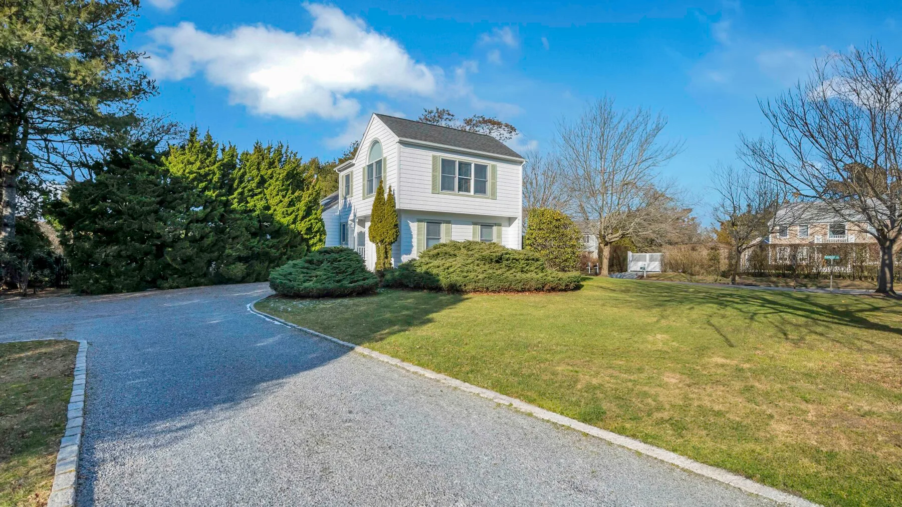 A two-story house stands beside a curved driveway and a broad lawn.