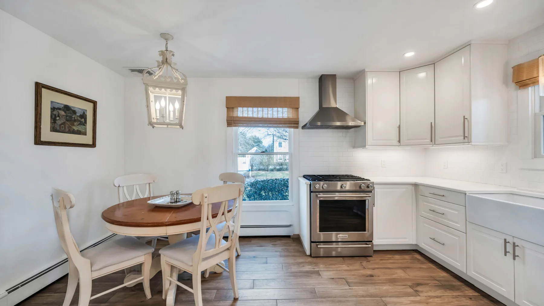 A bright kitchen with white cabinetry, a dining table, and a stainless-steel range.