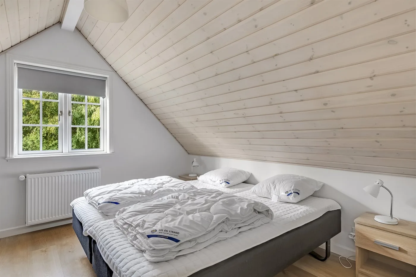 Dormitorio con una cama bajo un techo inclinado.