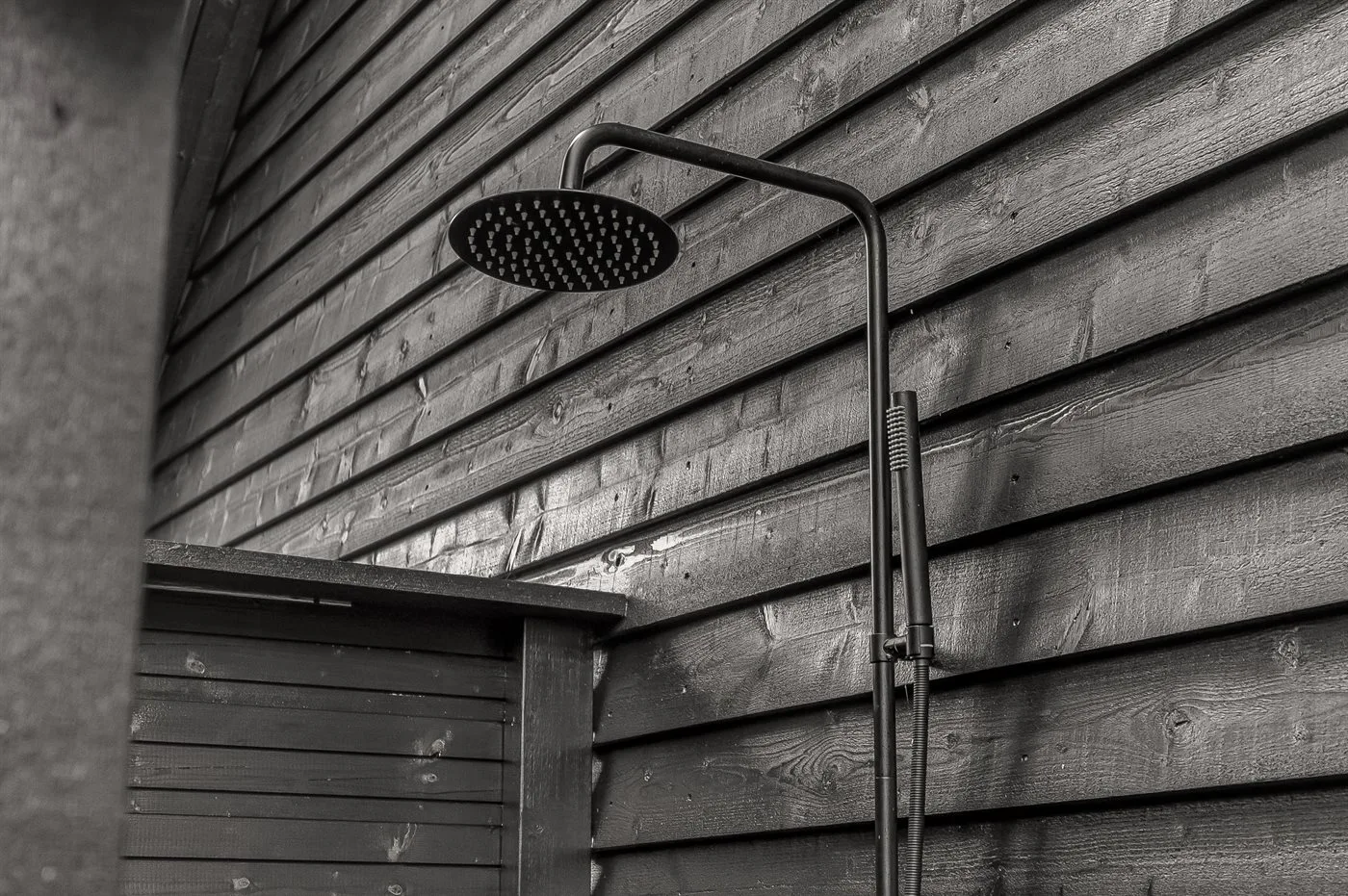 Ducha exterior junto a una pared de madera.