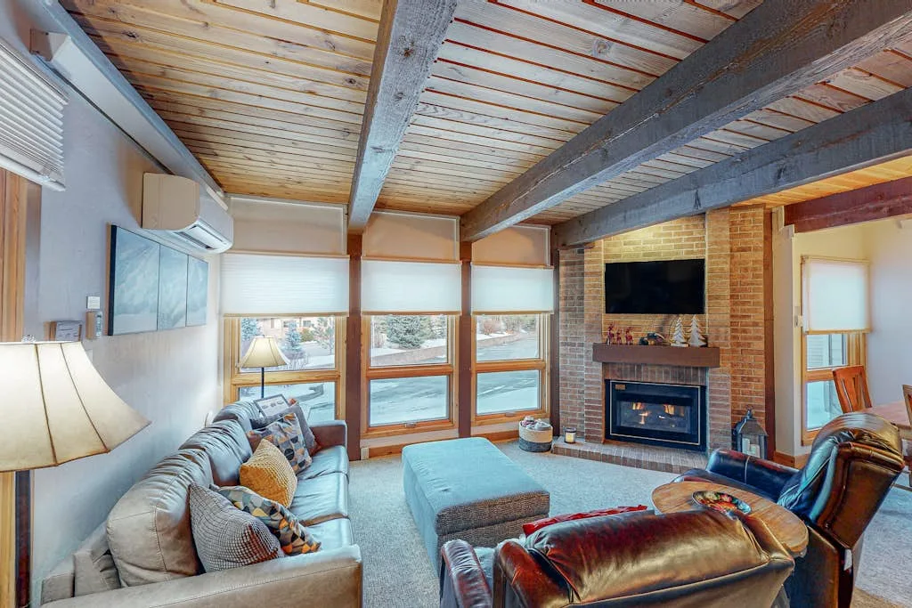 Una sala de estar con asientos, ventanas grandes y una chimenea.