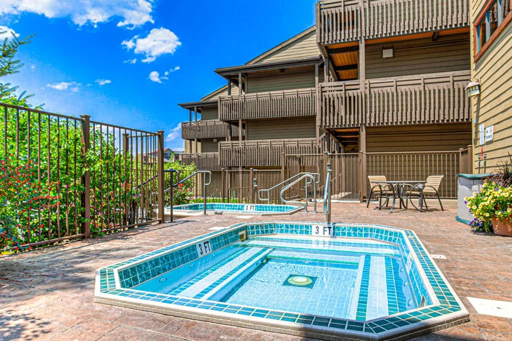 An outdoor pool area beside a multi-story building, with seating on the patio.