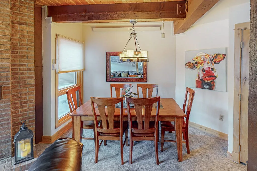 A dining area with a wooden table and chairs beneath exposed ceiling beams.