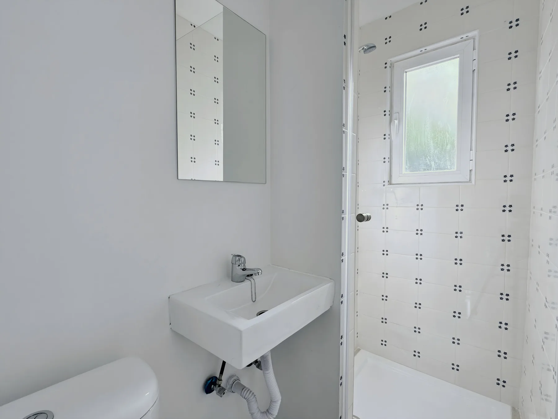A bright bathroom with a wall-mounted sink and a shower area.