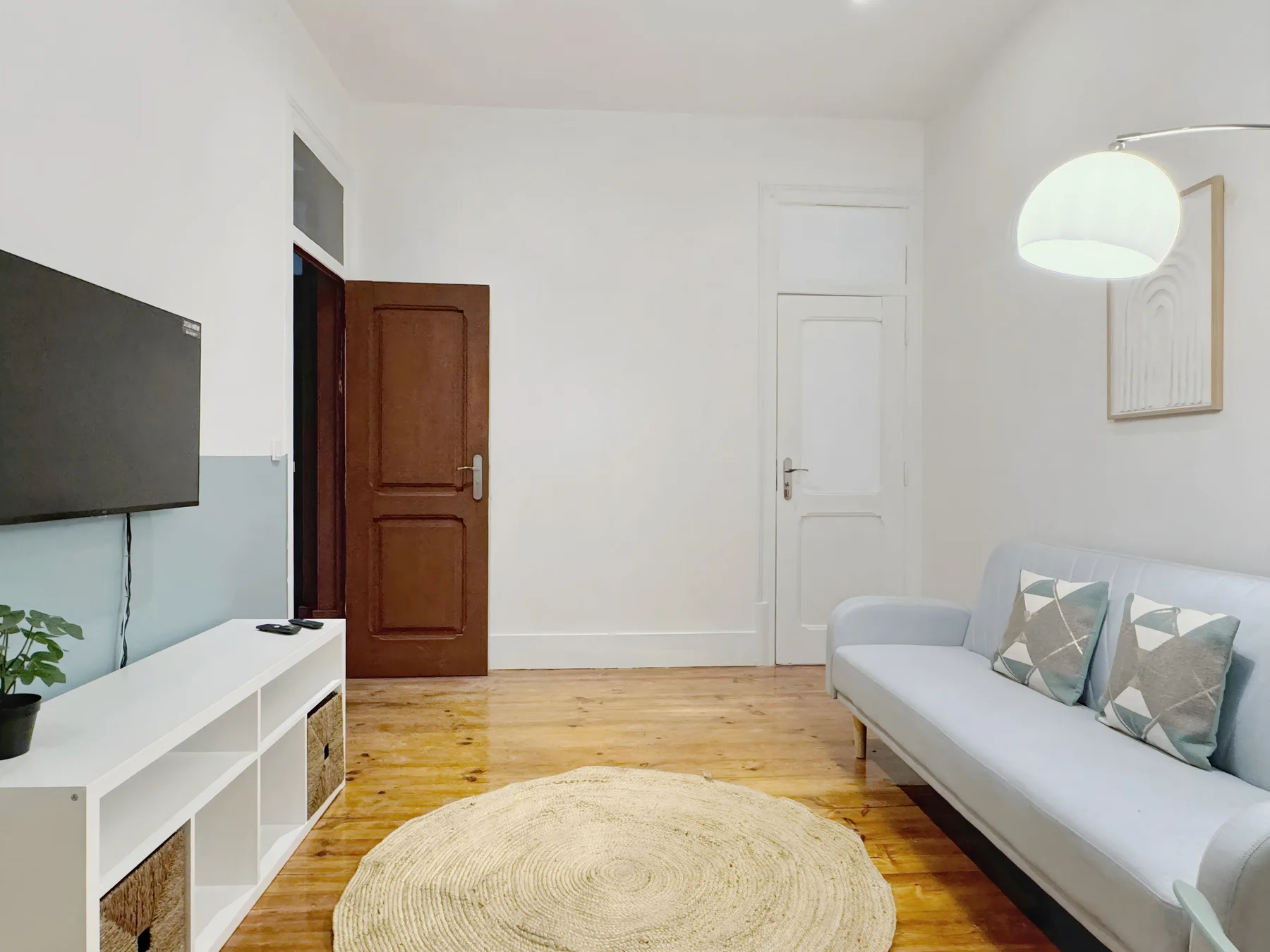 A bright living room with a light-colored sofa and a wooden floor.