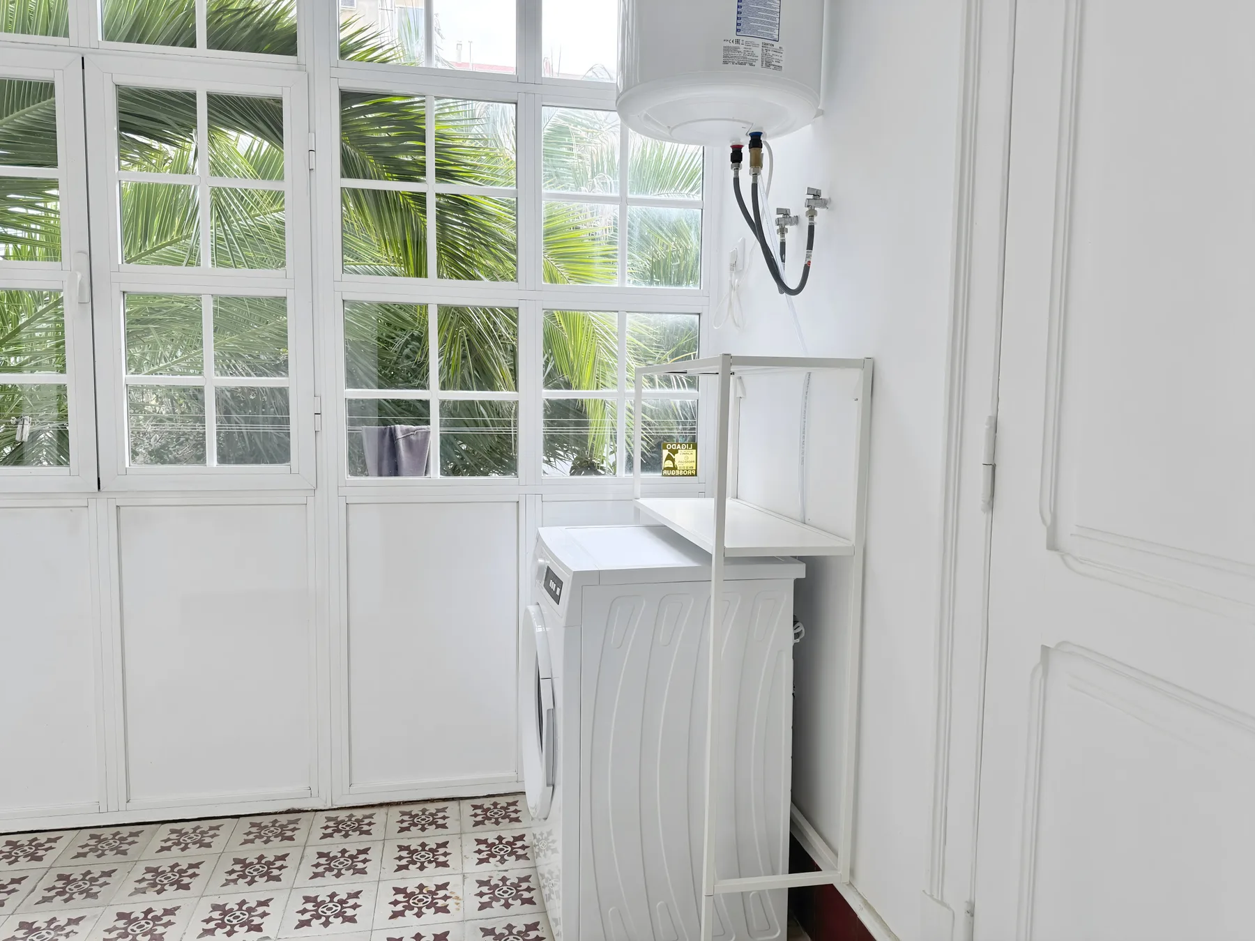 A bright laundry area with a washing machine beside large windows.