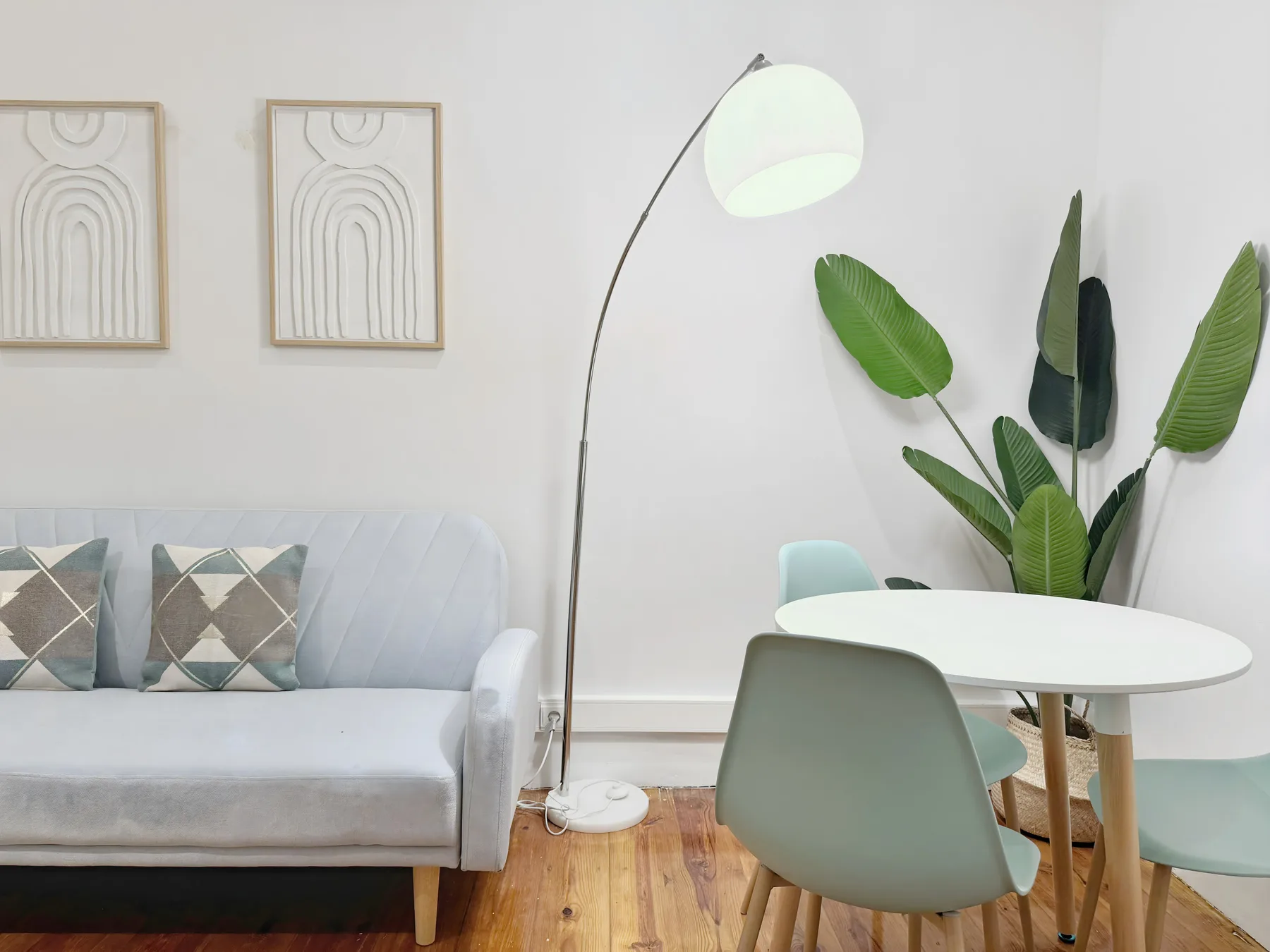 A living and dining area with a sofa, table, and leafy plant.