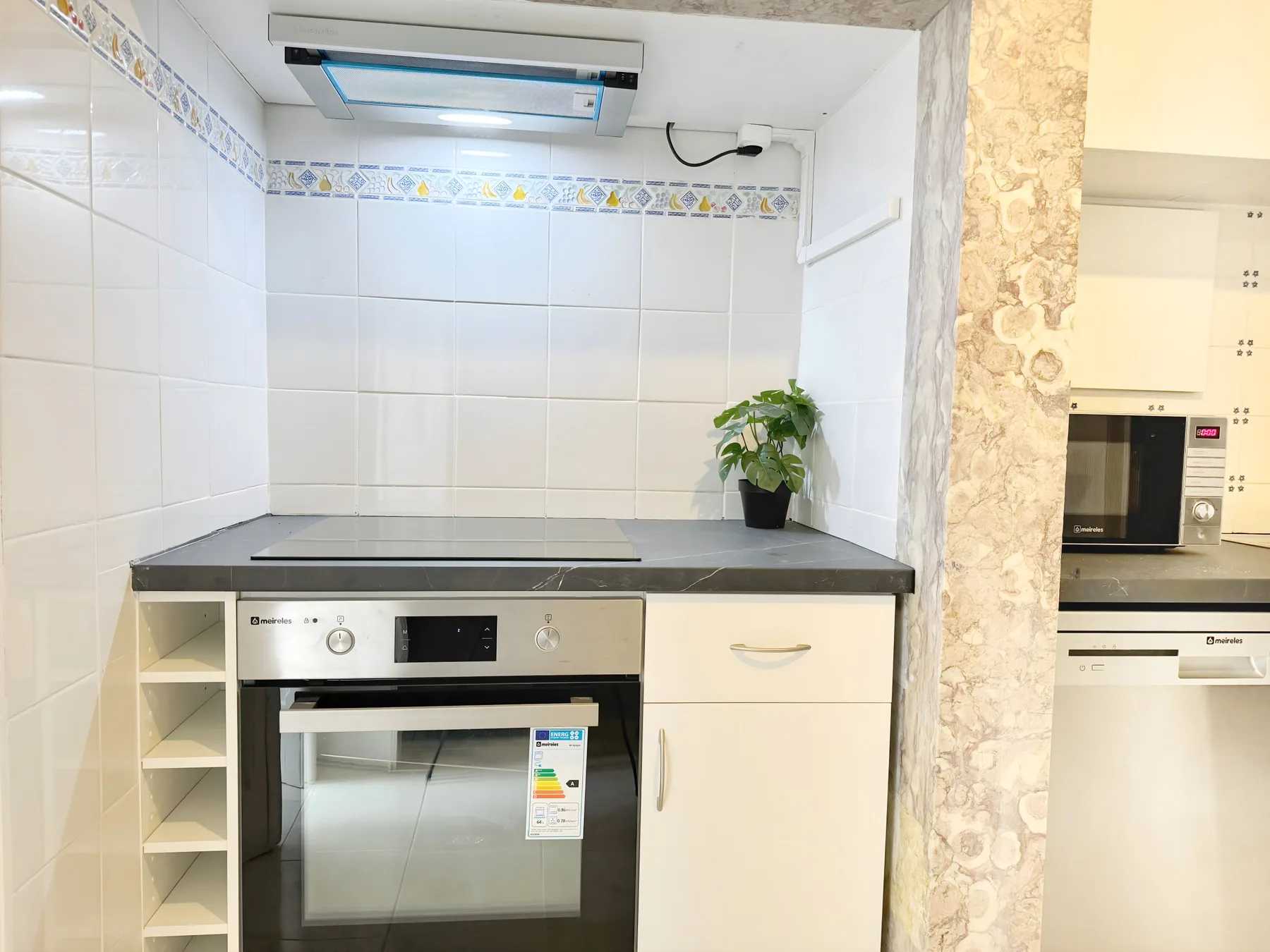 A bright kitchen with an oven beneath a dark countertop.